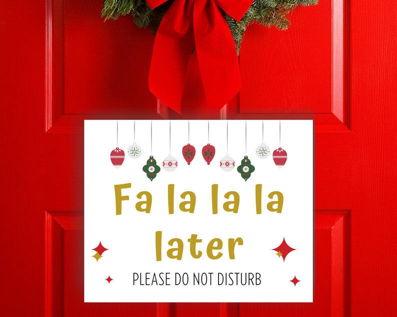 Fa la la la later, Please do not disturb written on a Christmas door sign with ornaments. The paper sign is against a red door with a christmas wreath.