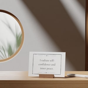 A self-confidence and peace mantra is shown next to a round mirror and green plant in a relaxing image.