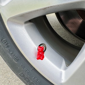 May include: A red gummy bear shaped tire valve stem cap.