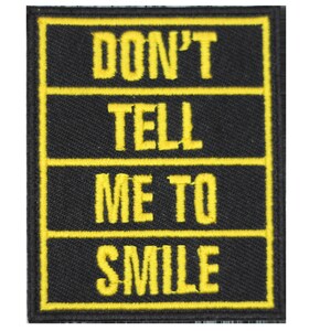 May include: Black fabric patch with yellow embroidered text that reads "DON'T TELL ME TO SMILE".