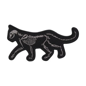 May include: Black embroidered iron-on patch of a cat skeleton. The cat is walking with its head turned to the left. The skeleton is a light grey colour.