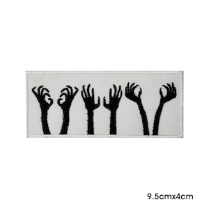 May include: White embroidered patch with five black silhouettes of hands reaching up. The patch measures 9.5 inches by 4 inches.