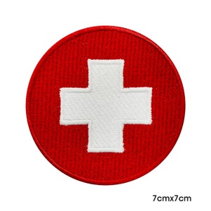 May include: Red embroidered patch with a white cross in the centre. The patch is 7cm by 7cm.