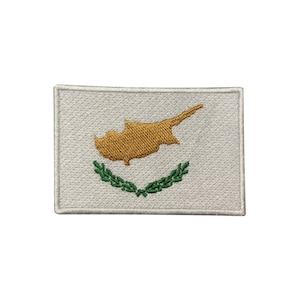 May include: An embroidered patch featuring the flag of Cyprus. The patch is white with a gold outline of the island of Cyprus and two green olive branches.