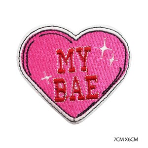 May include: A pink heart-shaped embroidered patch with the words "MY BAE" in red block letters. The patch has a black border and white accents, with dimensions of 7cm x 6cm.