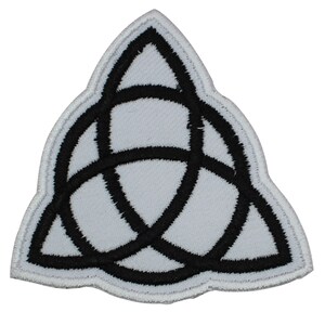 May include: White fabric patch with a black embroidered triquetra symbol. The triquetra is a three-pointed knot, also known as a trinity knot.