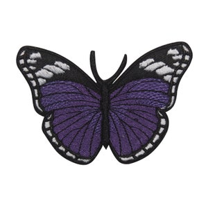 Könnte beinhalten: Lilafarbener Schmetterling-Stickerei-Aufnäher mit schwarzen und weißen Akzenten. Der Schmetterling hat ein detailliertes Design mit filigranen Flügeln.