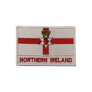 May include: White embroidered patch with the flag of Northern Ireland. The flag features a red cross on a white background with a red hand and a gold crown in the center. The text "NORTHERN IRELAND" is embroidered below the flag.