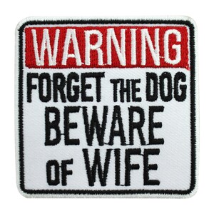 May include: White square patch with black embroidered text that reads "WARNING FORGET THE DOG BEWARE OF WIFE" with a red rectangular warning sign at the top that reads "WARNING".
