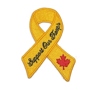 Könnte beinhalten: Gelbes Band mit dem Text "Support Our Troops" und einem roten Ahornblatt.