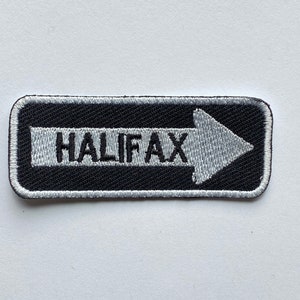 May include: Black and white embroidered patch with a white arrow pointing to the right and the word "HALIFAX" in white text.