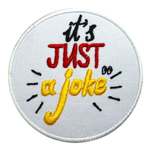 May include: White round embroidered patch with black text that reads "it's JUST a joke" with a yellow "a joke" and red "JUST".
