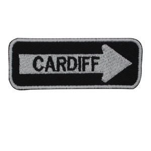 May include: Black and white embroidered patch with a white arrow pointing to the right and the word "CARDIFF" in black.