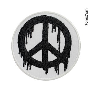 Peut inclure: Un écusson brodé blanc avec un symbole de paix noir qui coule de peinture noire. L'écusson mesure 7 cm de diamètre.