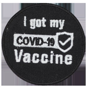 May include: A round, black patch with white embroidered text. The text reads "I got my COVID-19 Vaccine" with a checkmark inside a shield graphic. The patch is likely for clothing or accessories.