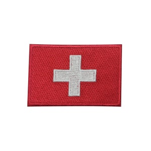 May include: A red embroidered patch with a white cross in the center. The patch is a representation of the Swiss flag.