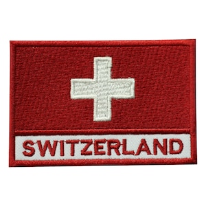 May include: Embroidered patch featuring the Swiss flag design. The patch has a red background with a white cross in the center. The word "SWITZERLAND" is embroidered in white on a white rectangular border at the bottom.