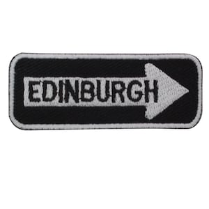 May include: Black and white embroidered patch with a white arrow pointing to the right and the word "EDINBURGH" in white letters.