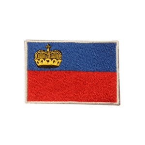 May include: A blue and red embroidered patch with a gold crown. The patch is surrounded by a white border.