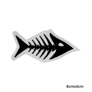 Peut inclure: Patch brodé blanc représentant un squelette de poisson noir, 8 cm sur 4 cm.