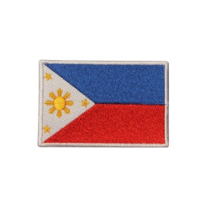 May include: An embroidered patch featuring the flag of the Philippines. The flag is white with a blue triangle at the hoist and a red field. The triangle features a yellow sun with eight rays and three five-pointed stars.