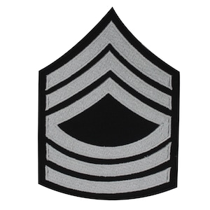 Könnte beinhalten: Ein silber gestickter Patch mit fünf Chevron auf schwarzem Hintergrund. Der Patch hat die Form eines spitz zulaufenden Rechtecks.