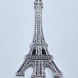 May include: A black and white embroidered iron-on patch of the Eiffel Tower.