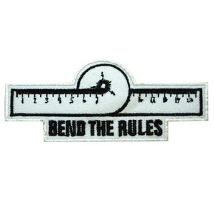 May include: White embroidered patch with a black ruler and a bullseye with a black circle around it. The text "Bend the Rules" is below the ruler.