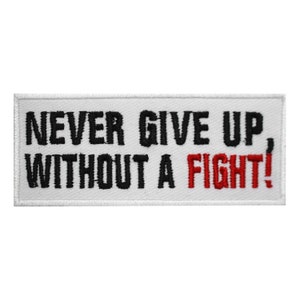 May include: White embroidered patch with black text that reads "Never Give Up, Without A Fight!" The word "Fight!" is in red.