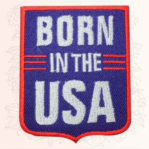 May include: A blue and red embroidered patch with the text "Born in the USA" in white lettering.