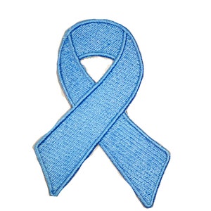 May include: A light blue ribbon patch with a stitched border. The ribbon is a symbol of awareness and support. The patch is designed to be ironed or sewn onto fabric.