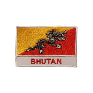 May include: An embroidered patch featuring the flag of Bhutan. The flag is yellow and red with a black dragon in the center. The words "BHUTAN" are printed below the flag.