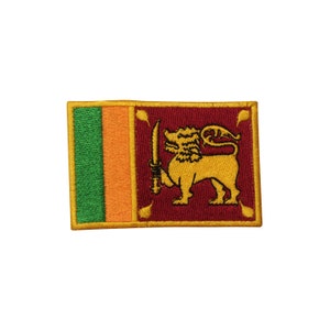 May include: An embroidered patch featuring the flag of Sri Lanka. The flag is red, orange, and green with a gold lion holding a sword in its right paw.