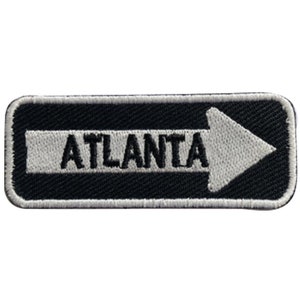 May include: Black and white embroidered patch with a white arrow pointing to the right and the word "ATLANTA" in black.