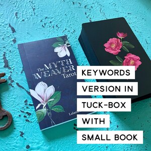 May include: A tarot deck with a navy blue tuck box and a small book. The tuck box features a white magnolia flower and the text "The Myth Weaver Tarot." The deck of cards has a black background with pink roses.