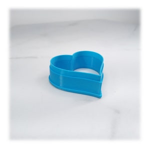 May include: A bright blue plastic heart-shaped cookie cutter.
