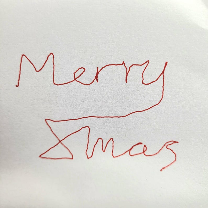May include: A white surface featuring the handwritten text Merry Xmas in red ink. The letters are formed with a single continuous line style, creating a casual and handwritten appearance across two lines of text on the plain white background.