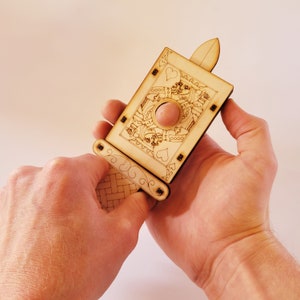 sword through finger magic trick. A plywood laser cut device.  Wooden hand held box decorated as the King of hearts playing card. A finger is pushed through a hole in the box.  A small wooden sword is then pushed into the box and out the other side