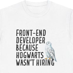 Peut inclure: T-shirt blanc avec l'inscription "FRONT-END DEVELOPER BECAUSE HOGWARTS WASN'T HIRING" en noir. Une illustration à l'aquarelle d'un harfang des neiges est à droite du texte. C'est un vêtement décontracté.