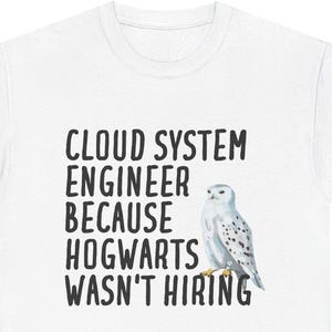 May include: White t-shirt featuring the text "CLOUD SYSTEM ENGINEER BECAUSE HOGWARTS WASN'T HIRING" in black. A watercolour illustration of a snowy owl is next to the text.