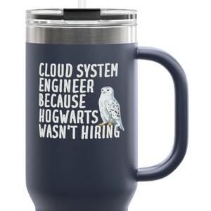 May include: Dark blue travel mug with a handle and a straw. The mug has the text "CLOUD SYSTEM ENGINEER BECAUSE HOGWARTS WASN'T HIRING" and a white owl illustration.