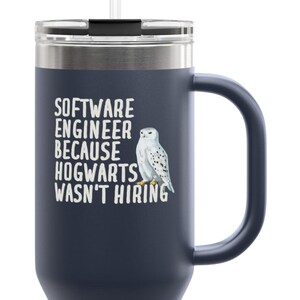 Może przedstawiać: Granatowy kubek podróżny z uchwytem i słomką. Kubek zawiera napis "SOFTWARE ENGINEER BECAUSE HOGWARTS WASN'T HIRING" oraz ilustrację sowy śnieżnej.