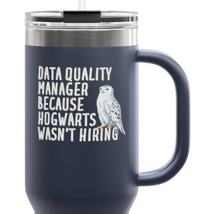 Puede incluir: Vaso térmico azul marino con asa y pajita. El vaso presenta el texto "DATA QUALITY MANAGER BECAUSE HOGWARTS WASN'T HIRING" y una ilustración de un búho nival.
