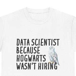 Może przedstawiać: Biała koszulka z czarnym napisem "DATA SCIENTIST BECAUSE HOGWARTS WASN'T HIRING". Po prawej stronie tekstu znajduje się akwarelowa ilustracja sowy śnieżnej. Odzież codzienna.