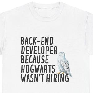 Könnte beinhalten: Weißes T-Shirt mit dem Text "BACK-END DEVELOPER BECAUSE HOGWARTS WASN'T HIRING" in Schwarz. Rechts vom Text befindet sich eine Aquarellillustration einer Schnee-Eule. Das T-Shirt ist ein Freizeitartikel.