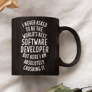 May include: Black coffee mug with white text that reads "I never asked to be the world's best software developer but here I am absolutely crushing it".