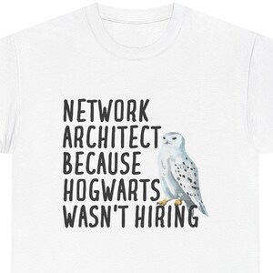 Peut inclure: T-shirt blanc avec l'inscription noire "NETWORK ARCHITECT BECAUSE HOGWARTS WASN'T HIRING". Une illustration à l'aquarelle d'un harfang des neiges est à droite du texte. Le t-shirt est en matière souple.