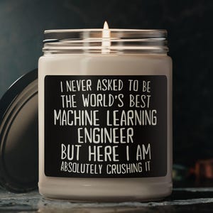 Peut inclure: Une bougie blanche avec une étiquette noire qui dit "Je n'ai jamais demandé à être le meilleur ingénieur en apprentissage automatique du monde, mais me voilà, je le démolit complètement."