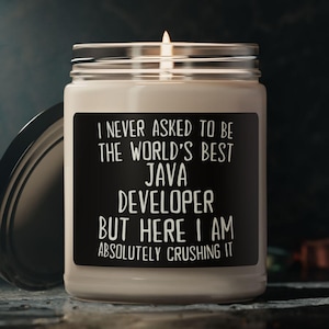 以下が含まれることがあります： 黒いラベルが付いたガラス瓶に入った、火の灯ったキャンドル。ラベルには「I NEVER ASKED TO BE THE WORLD'S BEST JAVA DEVELOPER BUT HERE I AM ABSOLUTELY CRUSHING IT」と書かれています。