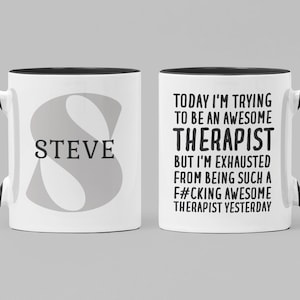Puede incluir: Taza de cerámica blanca con borde y asa negros. La taza tiene una letra "S" gris con el nombre "STEVE" impreso debajo. El otro lado de la taza tiene texto negro que dice "TODAY I'M TRYING TO BE AN AWESOME THERAPIST BUT I'M EXHAUSTED FROM BEING SUCH A F#CKING AWESOME THERAPIST YESTERDAY."